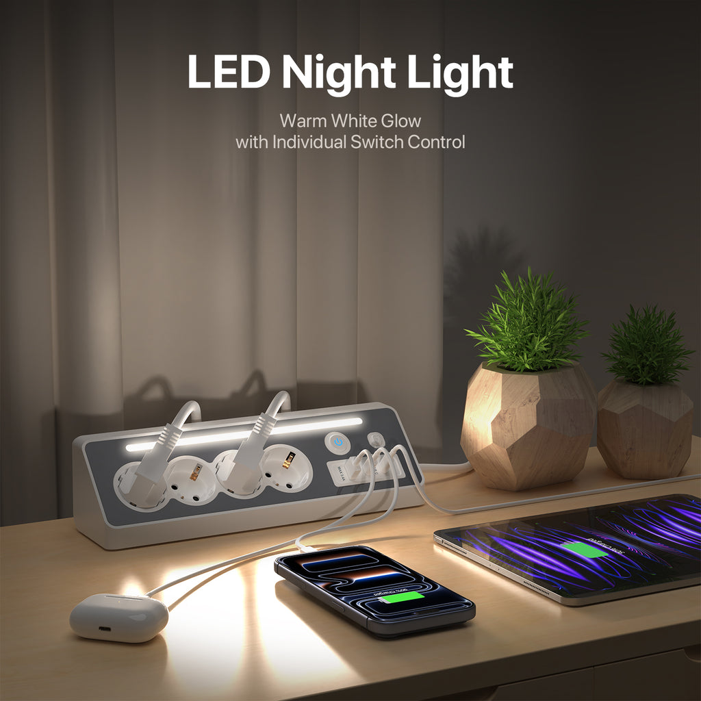A desktop power strip with integrated LED night lighting shown on a wooden table, with a smartphone and earbud case charging under warm white light. Text at the top reads 'LED Night Light' and 'Warm White Glow with Individual Switch Control.